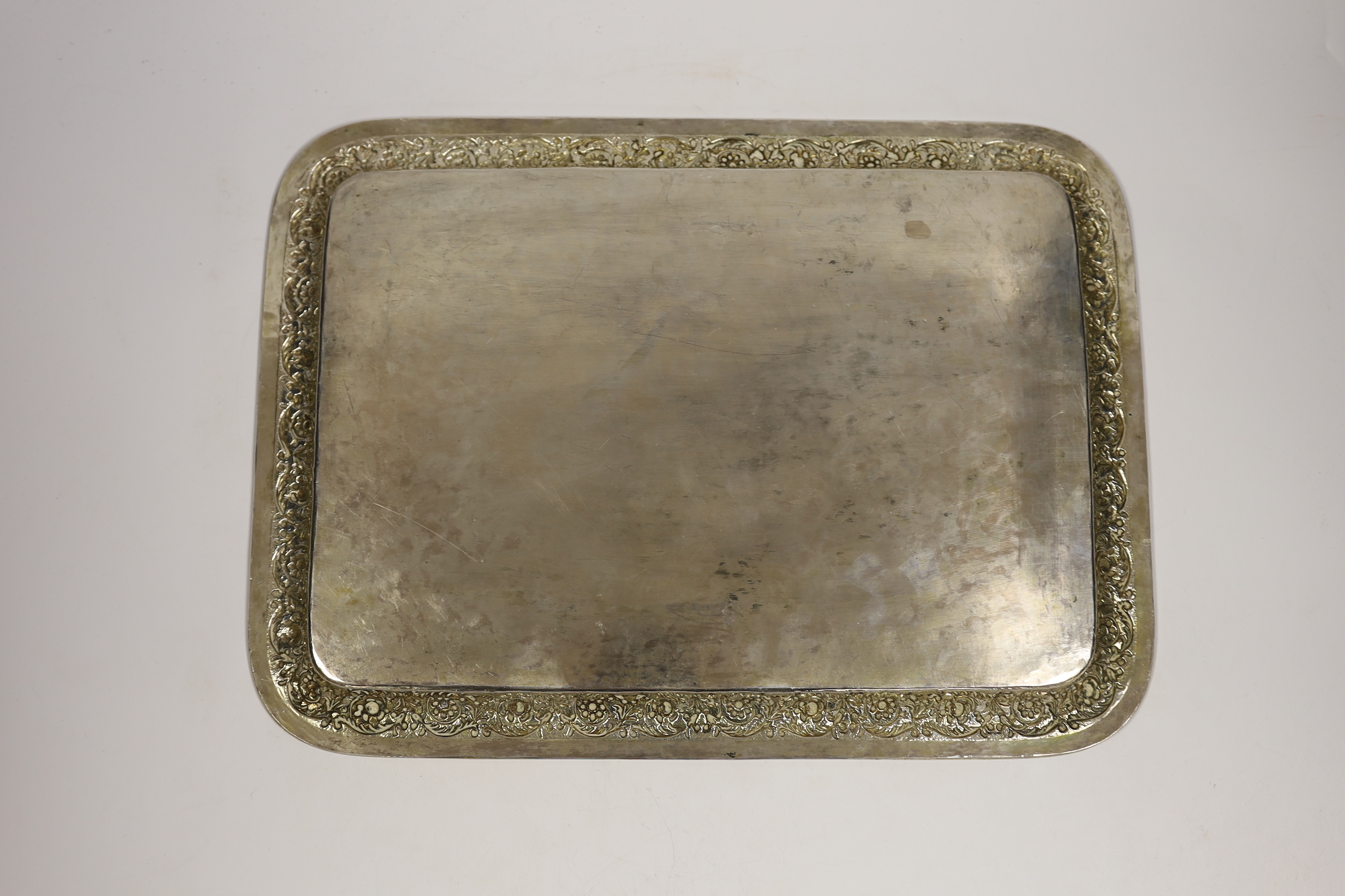 A Persian? engraved white metal tea tray, with embossed foliate border, 42cm, 46.4oz.